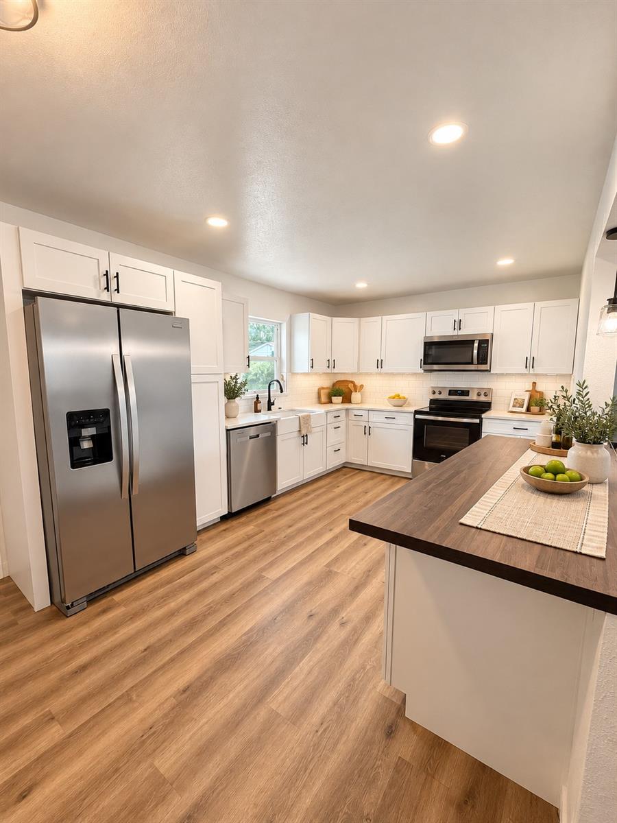 Virtually styled kitchen showcasing generous counter space, white cabinetry, and stainless steel appliances.