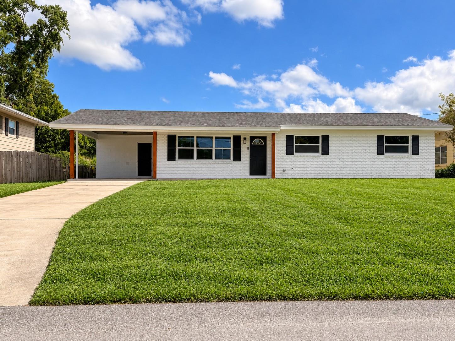 single-story, 3-bedroom, 2-bathroom, + bonus room, home featuring a white brick exterior, covered carport, and spacious front lawn.