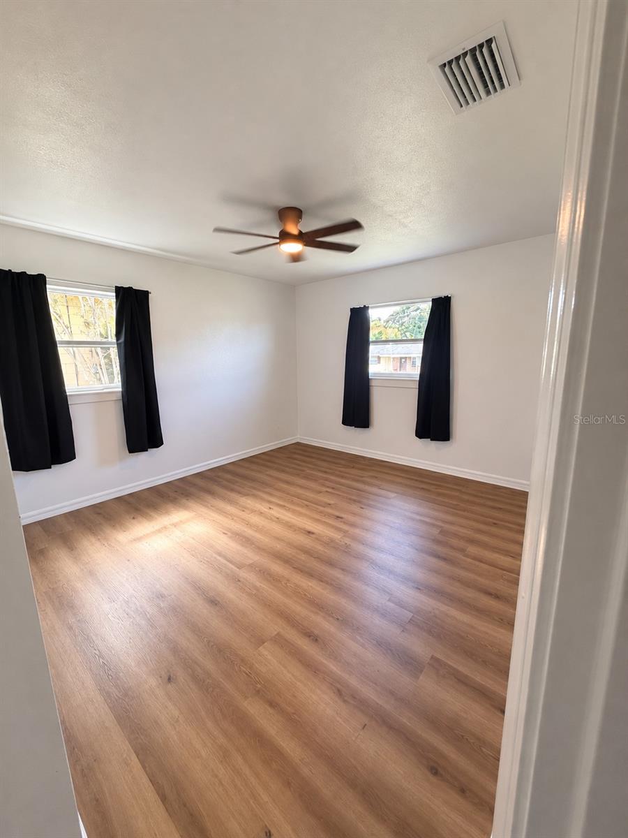 Flexible bedroom space with wood-look flooring, neutral finishes, and natural light and built in closet