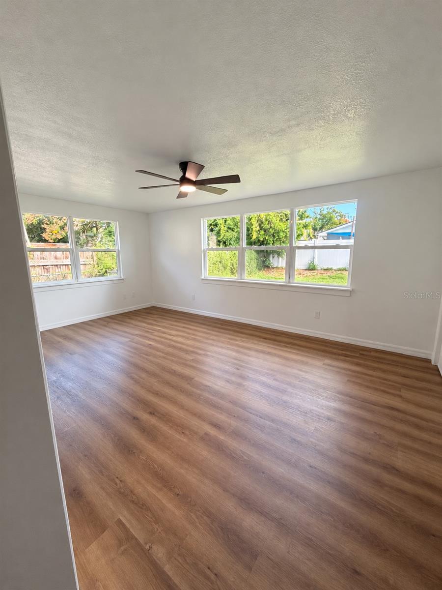 Spacious dining area with or bonus room with wood-look flooring and large windows overlooking the backyard.