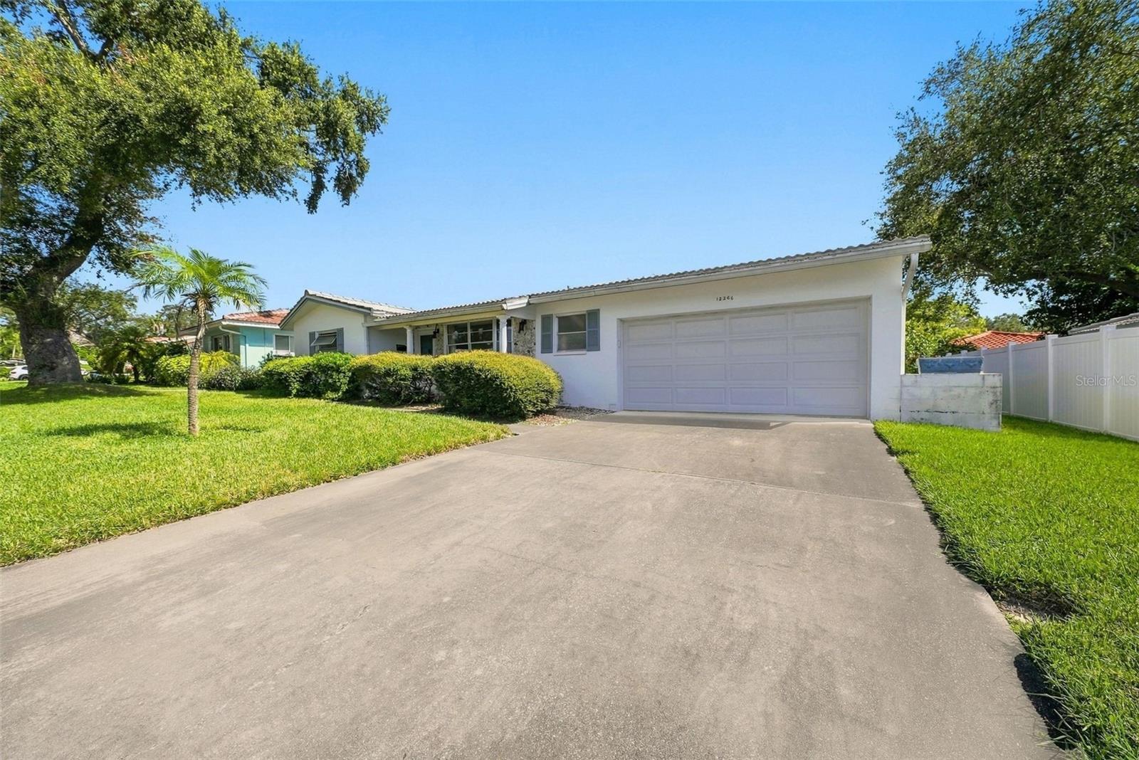 Front exterior view featuring extended concrete driveway and attached garage with well maintained lawn