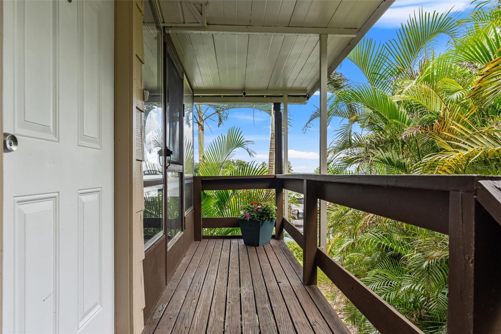Surrounded by lush tropical palms, the covered upper-level entry offers a welcoming approach to the home, complete with wood decking, railings, and protection from the elements.