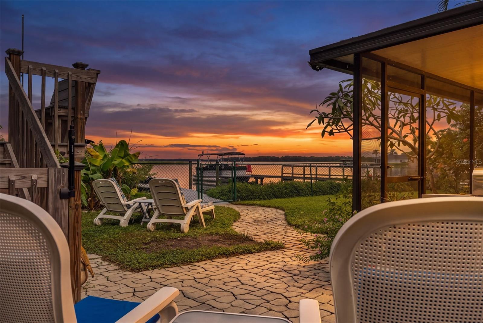Imagine ending your day with this view! Brilliant shades of orange, pink, and purple stretch across the sky as the sun sets over the water. From the backyard patio, enjoy the peaceful waterfront setting, tropical landscaping, and the private dock just steps away. This is what Florida waterfront living is all about.