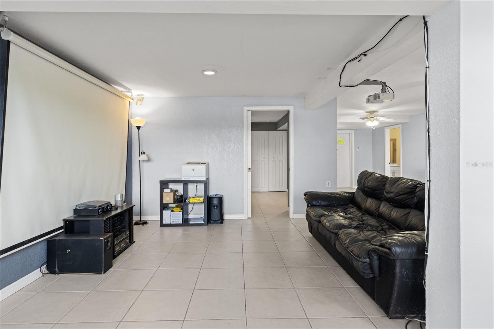 Bring the movie theater experience home with this lower-level entertainment space featuring a large projection screen and ceiling-mounted projector. The room offers space for comfortable seating and entertainment equipment, creating an inviting setting for movies, sports, and gatherings.