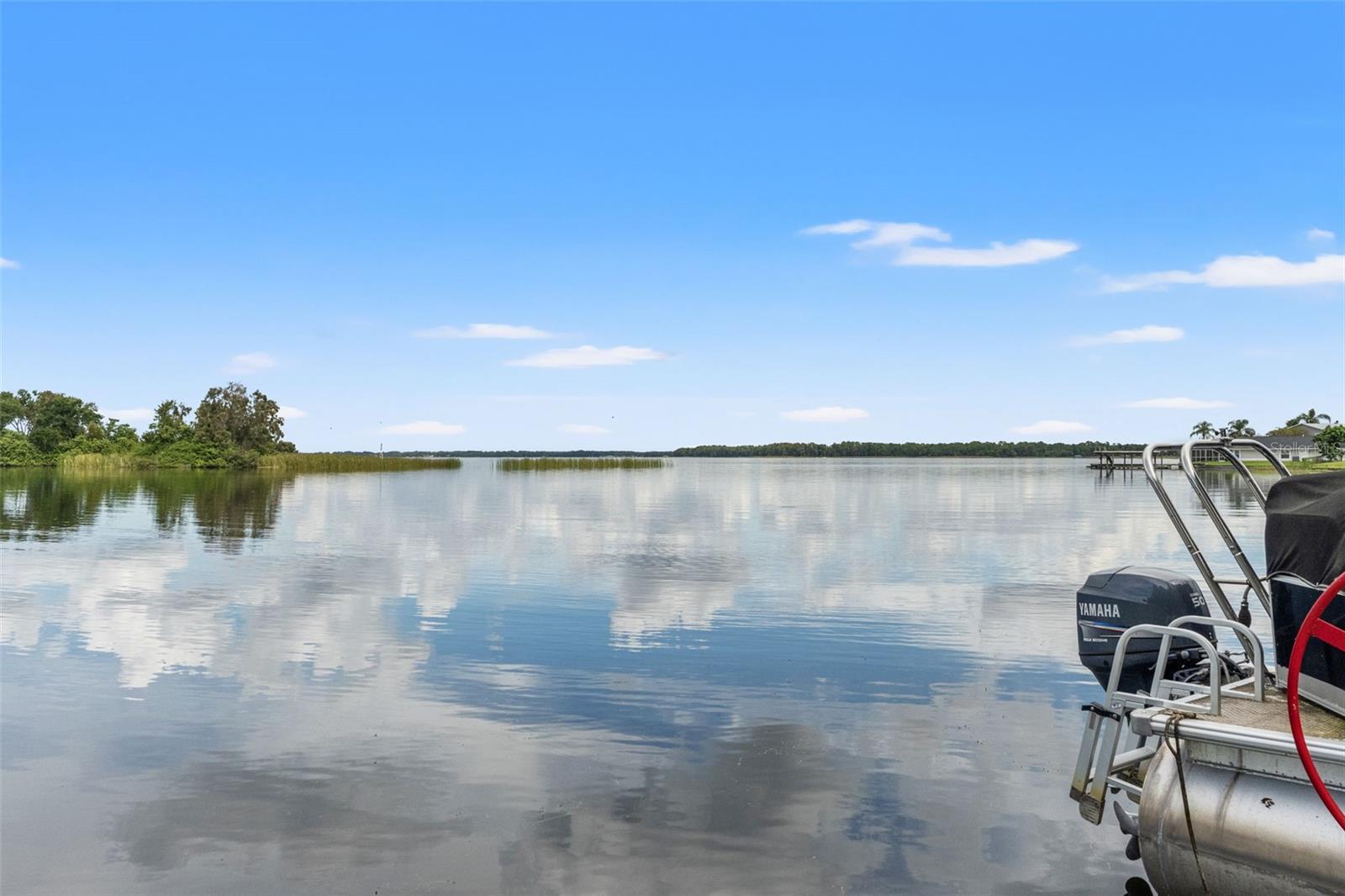 This is what lakefront living is all about! Sweeping views extend across the calm water toward a distant tree-lined shoreline. Whether you're enjoying an early morning sunrise, watching passing wildlife, or heading out for an afternoon on the boat, the waterfront setting is the star.
