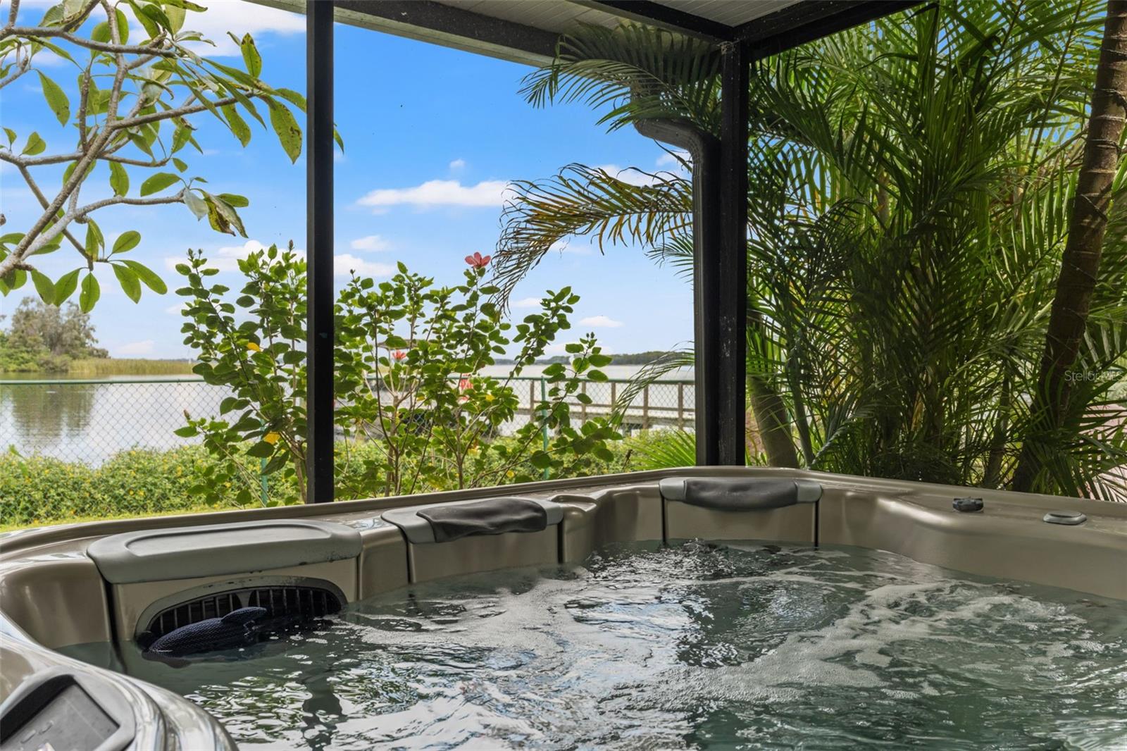 Imagine soaking in the bubbling hot tub while looking out toward the water! Tropical palms and flowering landscaping create a lush backdrop, while the screened enclosure makes this an inviting place to enjoy the outdoors.