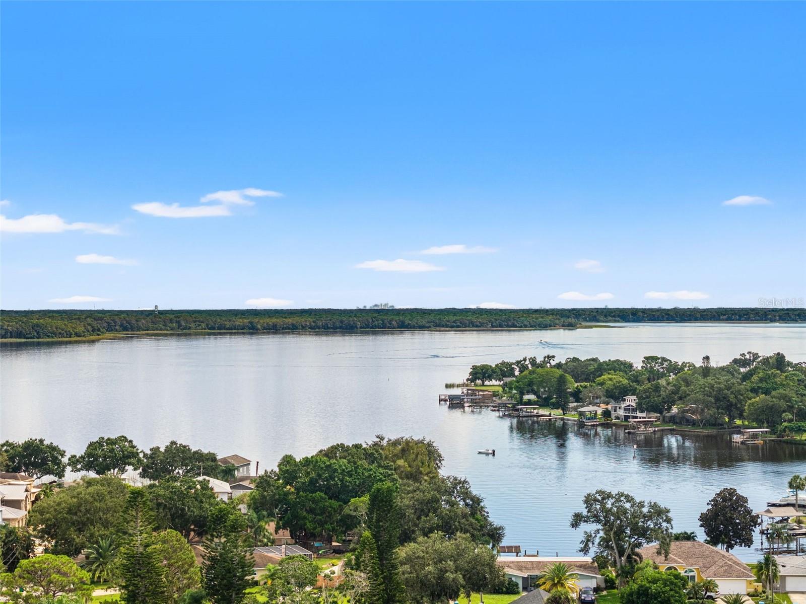 An expansive aerial view captures the beauty of the lake, with broad stretches of open water, natural shoreline vegetation, and distant tree-lined banks. It's a setting that invites afternoons on the boat, peaceful mornings by the water, and an appreciation for Florida's natural scenery.