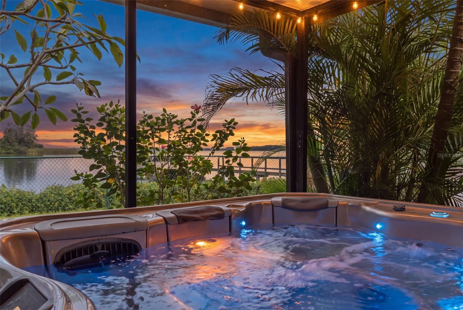Imagine soaking in the hot tub as the sun sets over the water! Tropical palms provide a sense of privacy, while the screened enclosure lets you enjoy the outdoors in comfort. A beautiful setting to unwind at the end of the day.