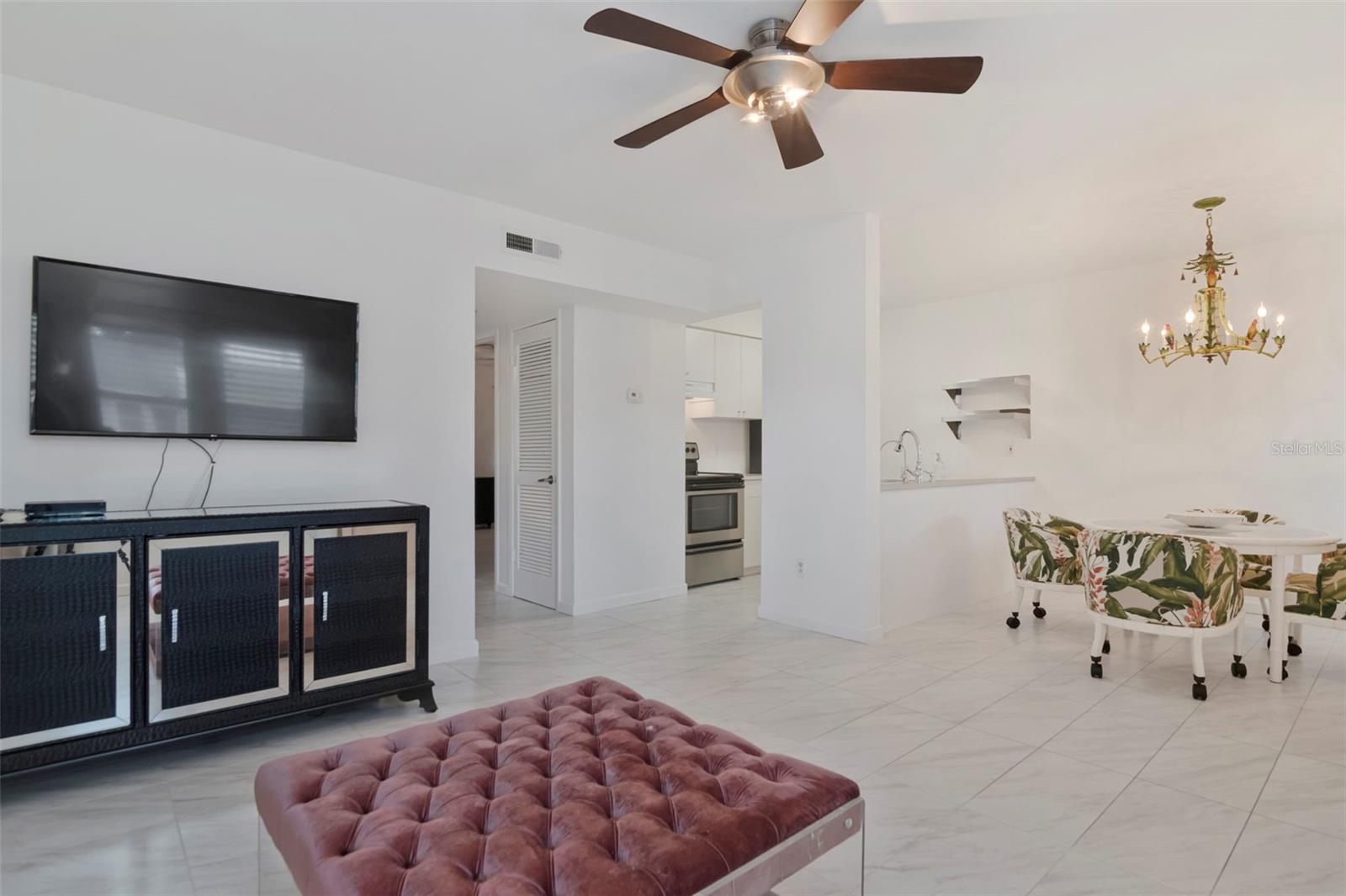 Open-concept living and dining area featuring tile flooring throughout, a modern ceiling fan, and stylish accent seating. Open-concept living and dining area featuring tile flooring throughout, a modern ceiling fan, and stylish accent seating.