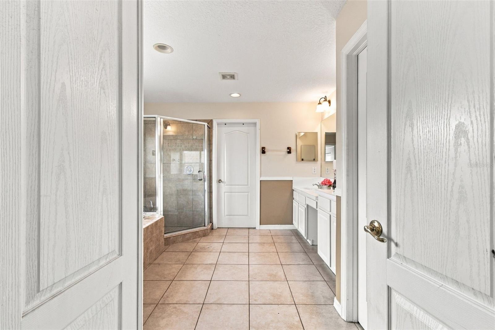 The primary bathroom entry features double doors offering a spa like feel.