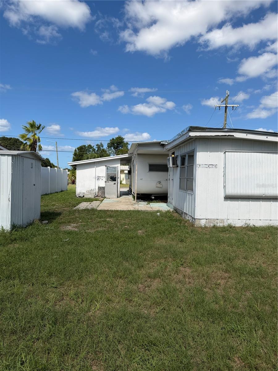 View of the fenced in backyard.  Building on the left is storage and the laundry room is across from the main mobile.