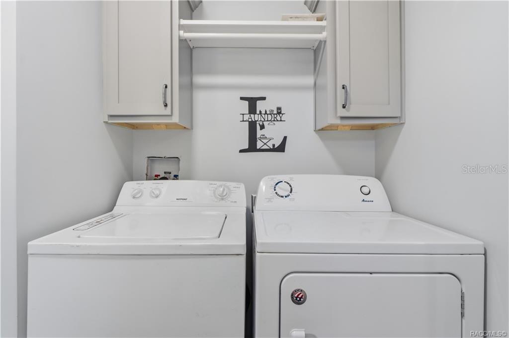 LAUNDRY MADE CONVENIENT! The INDOOR LAUNDRY AREA features a washer, dryer, overhead GRAY CABINETRY & shelving for additional storage.