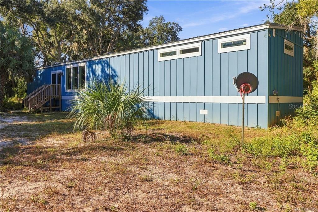 A LITTLE BIT COUNTRY, A LOT TO LOVE! The home's attractive BLUE EXTERIOR, WHITE TRIM & METAL ROOF complement the surrounding natural Florida landscape.