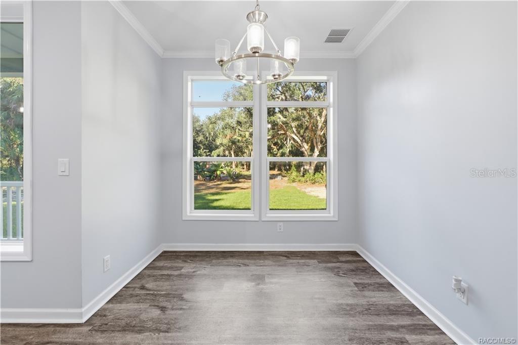 GATHER AROUND THE TABLE! The DINING AREA features a contemporary chandelier, attractive flooring & large windows framing views of the wooded property.