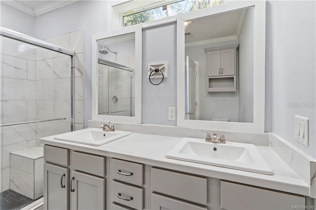 A BEAUTIFULLY FINISHED PRIMARY BATH! Enjoy a DOUBLE-SINK VANITY w/GRAY CABINETRY, marble-look countertops, framed mirrors & a spacious WALK-IN SHOWER.