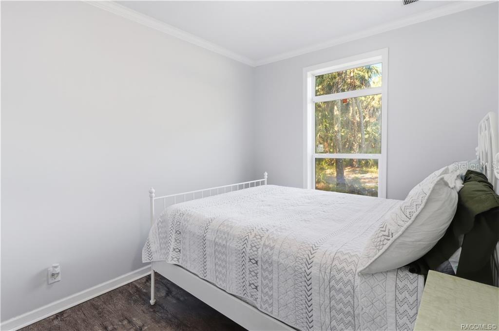 WAKE UP TO NATURE! Another view of the bedroom showcases natural light, attractive flooring & peaceful views of the surrounding trees.