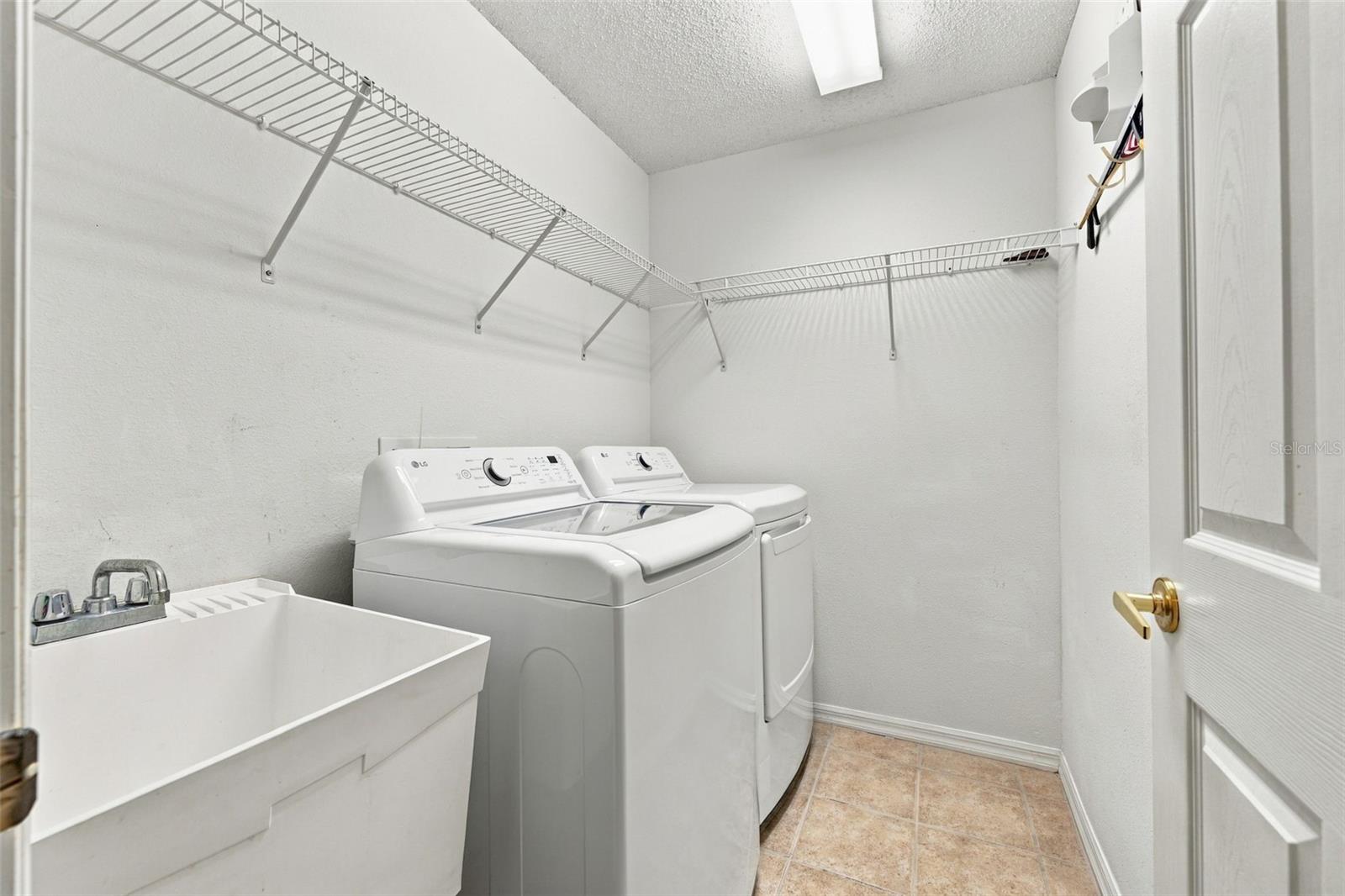Indoor laundry area with sink and storage