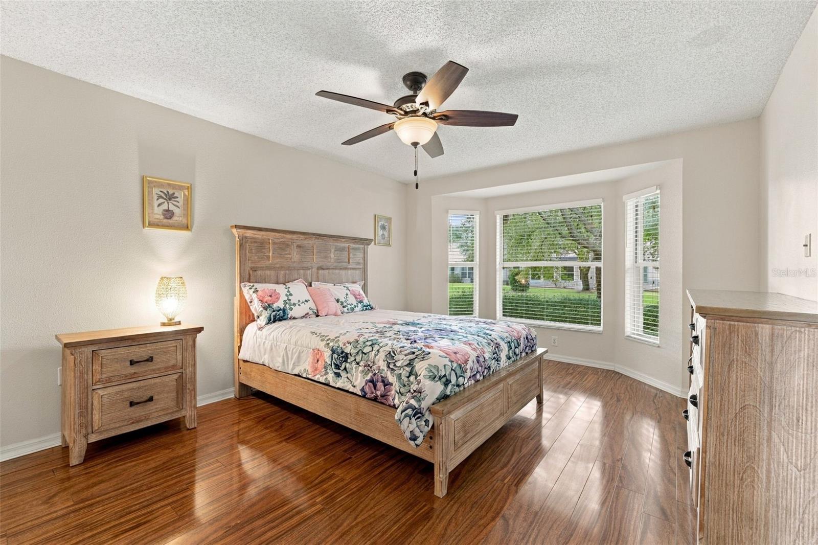 Primary Bedroom with a bay window, ceiling fan and laminate flooring