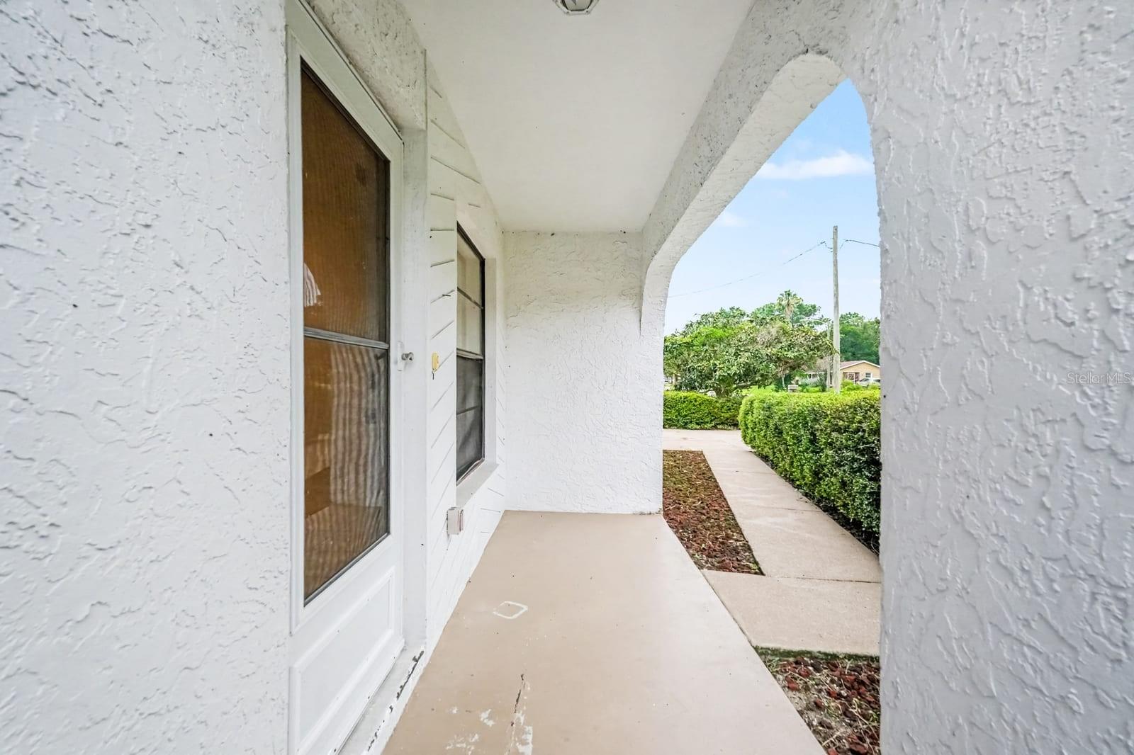 Covered Porch with Double Doors Opens to Manicured Grounds