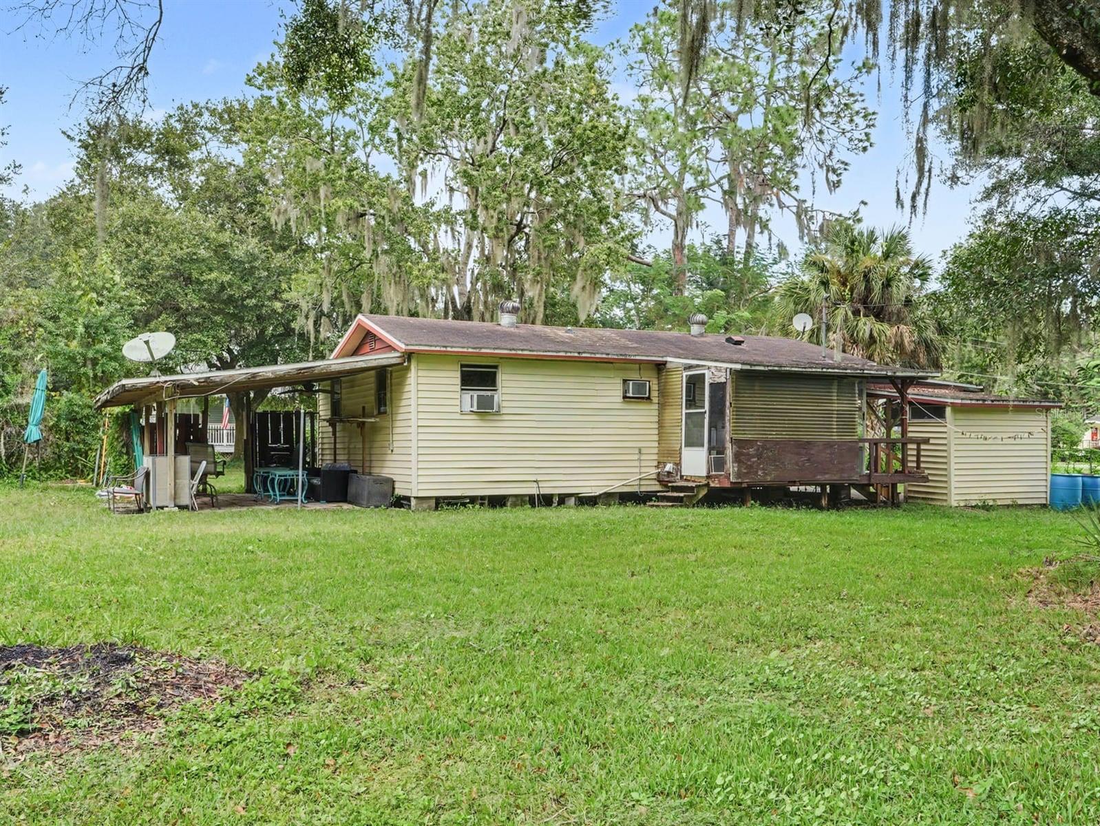 Mobile home with covered porch and mature landscape setting