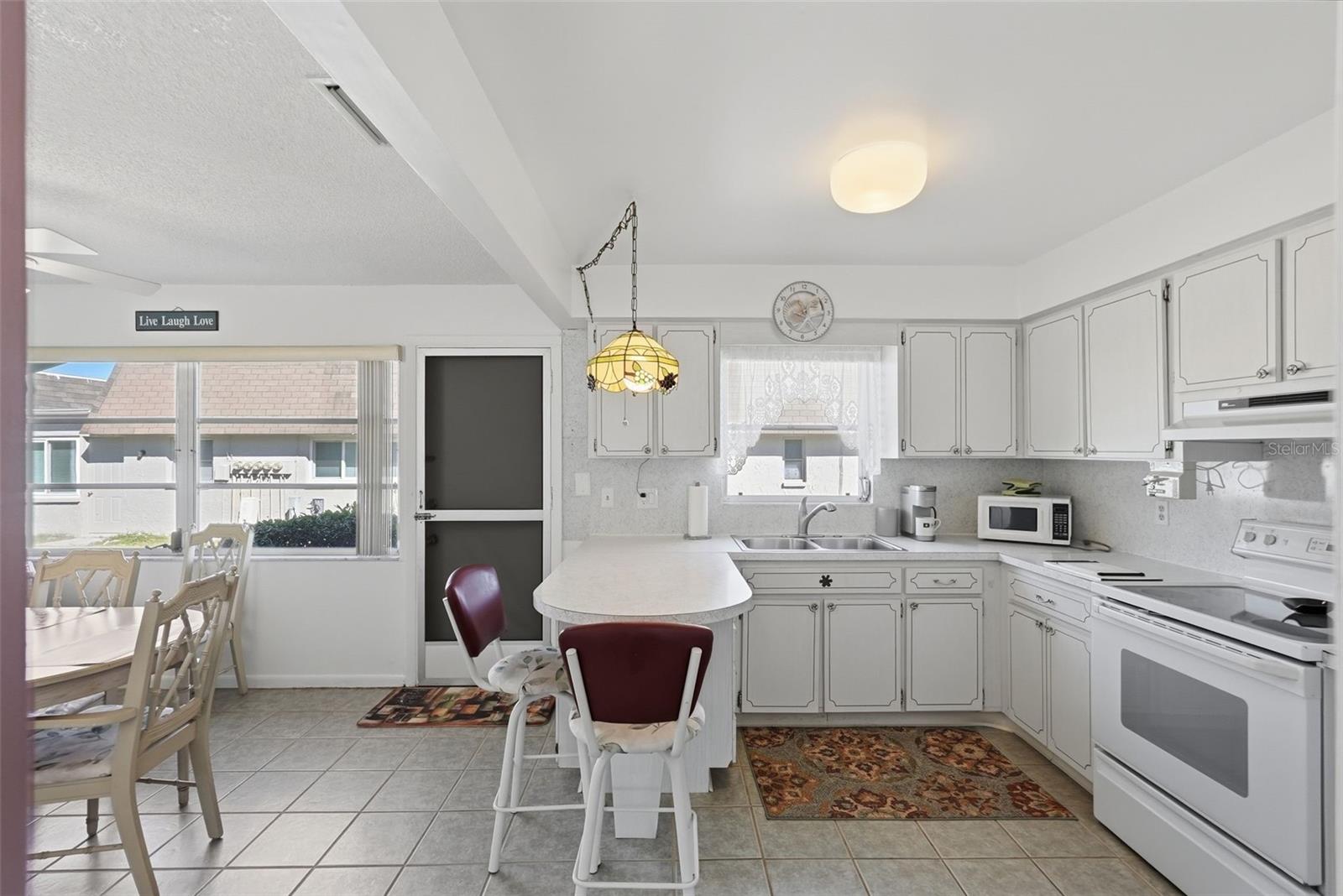 Bright kitchen with white cabinetry, appliances, and adjacent dining space.