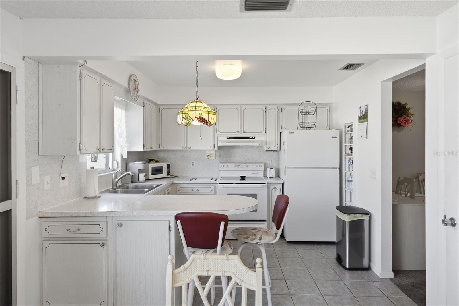 Open view of the kitchen and dining area with bright white finishes.