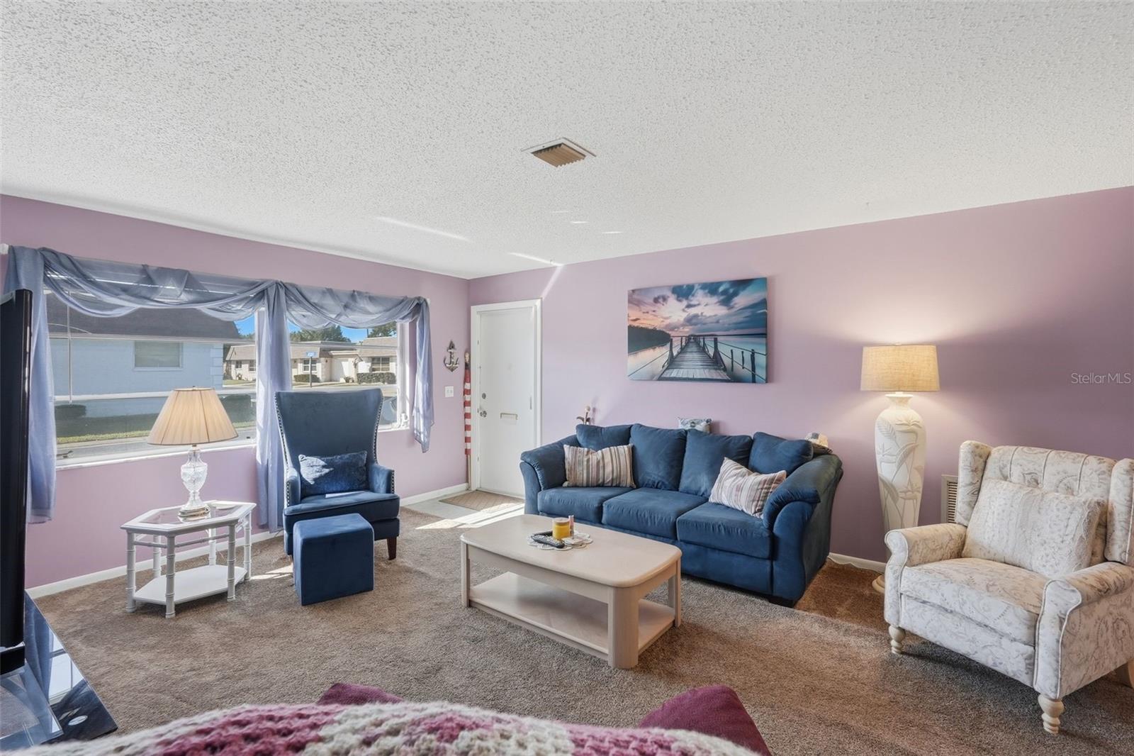 Another view of the bright living room with large windows and natural light. Another view of the bright living room with large windows and natural light.