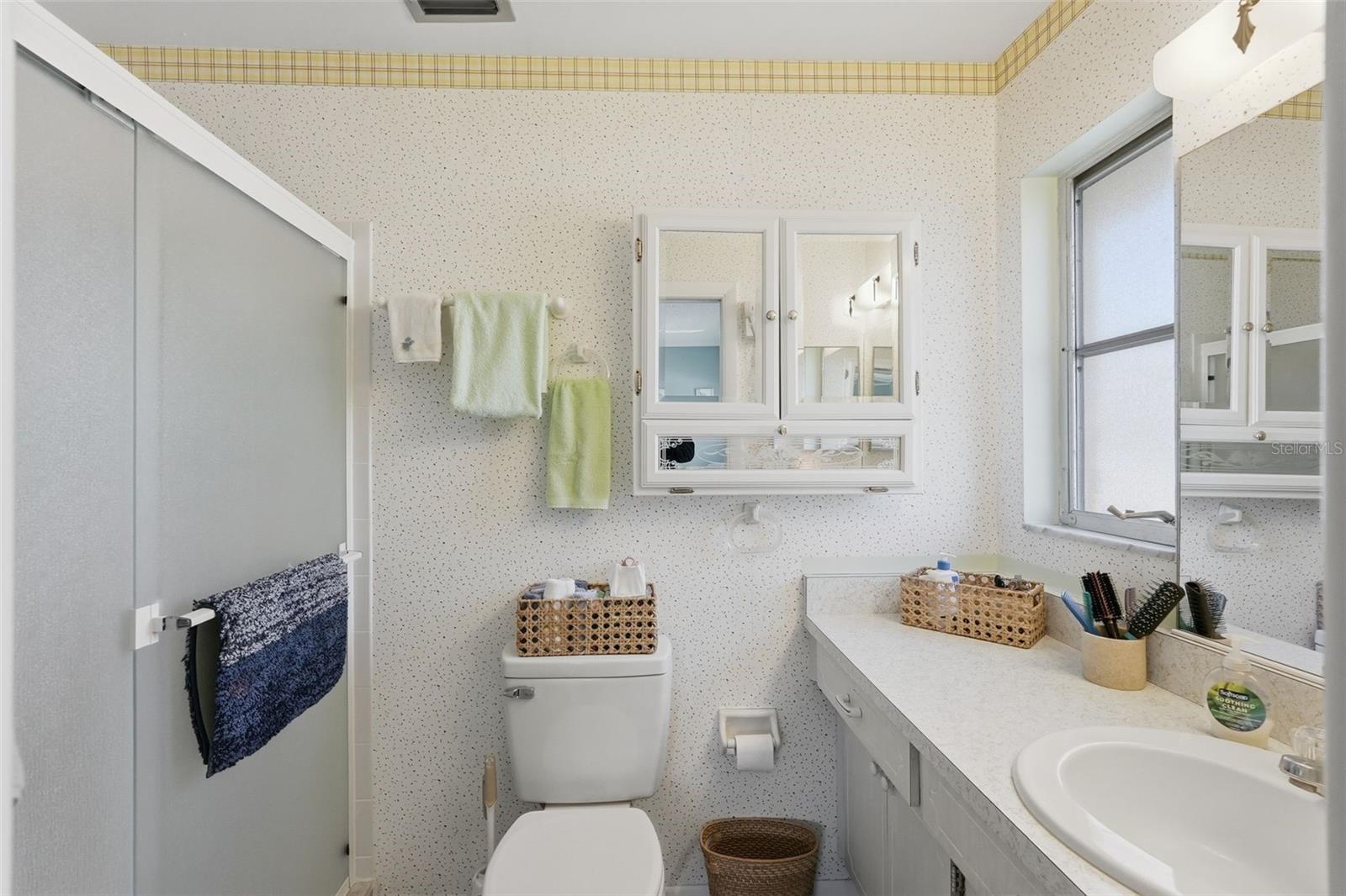 Primary bathroom featuring a vanity, storage, and bright finishes.