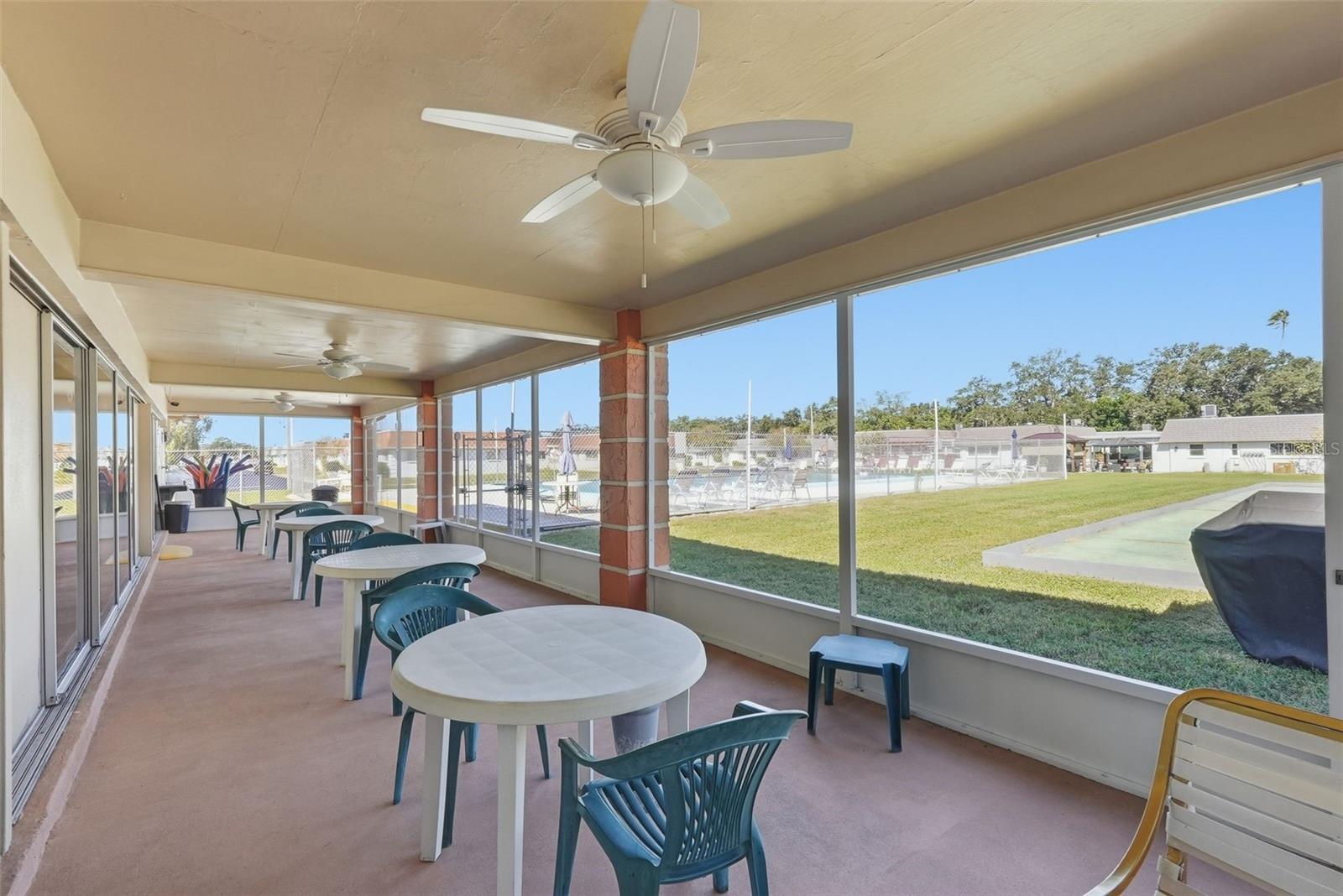 Covered community patio with shaded seating and views of the recreation area.