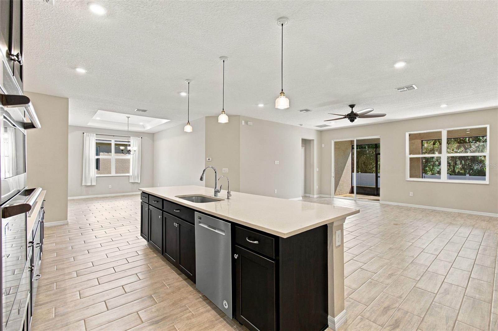 Center island with dishwasher - in the background, living room and patio to the right and dining room to the left