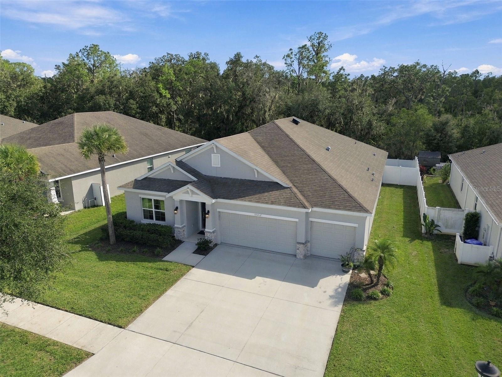 Angled overhead view of home's front exterior with conservation in background