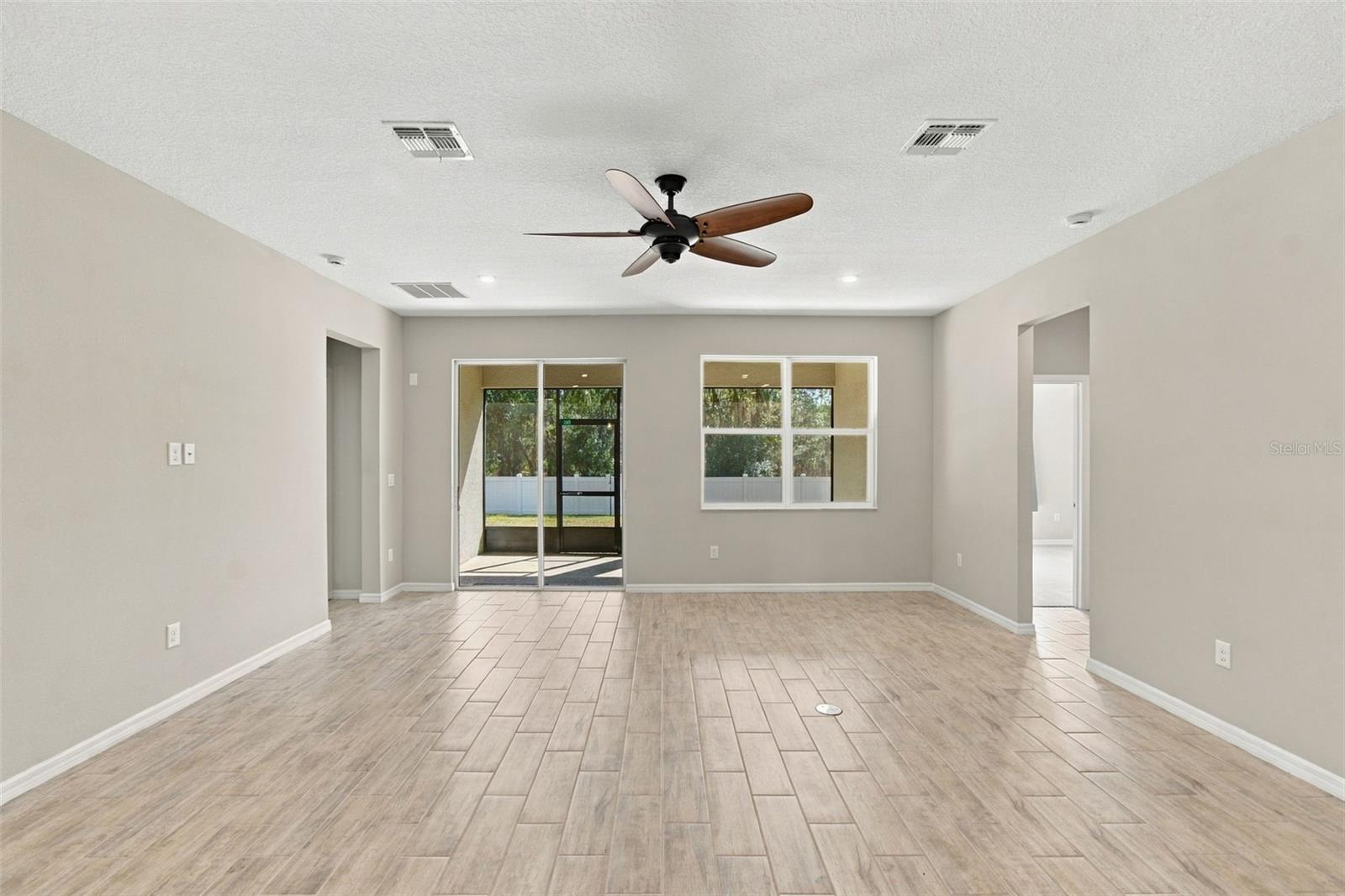 Living Room - to the left: entrance to primary suite,  to the right: hall leading to two additional bedrooms and full bath - screened in patio in background