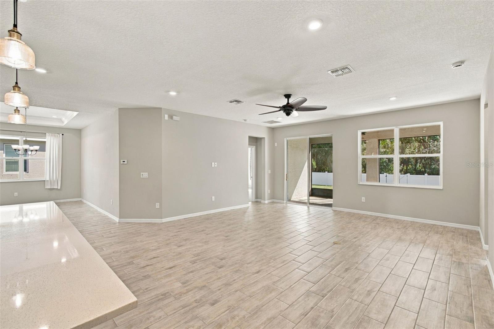 Spacious living room with ceiling fan - patio in background to the right, dining room to the left
