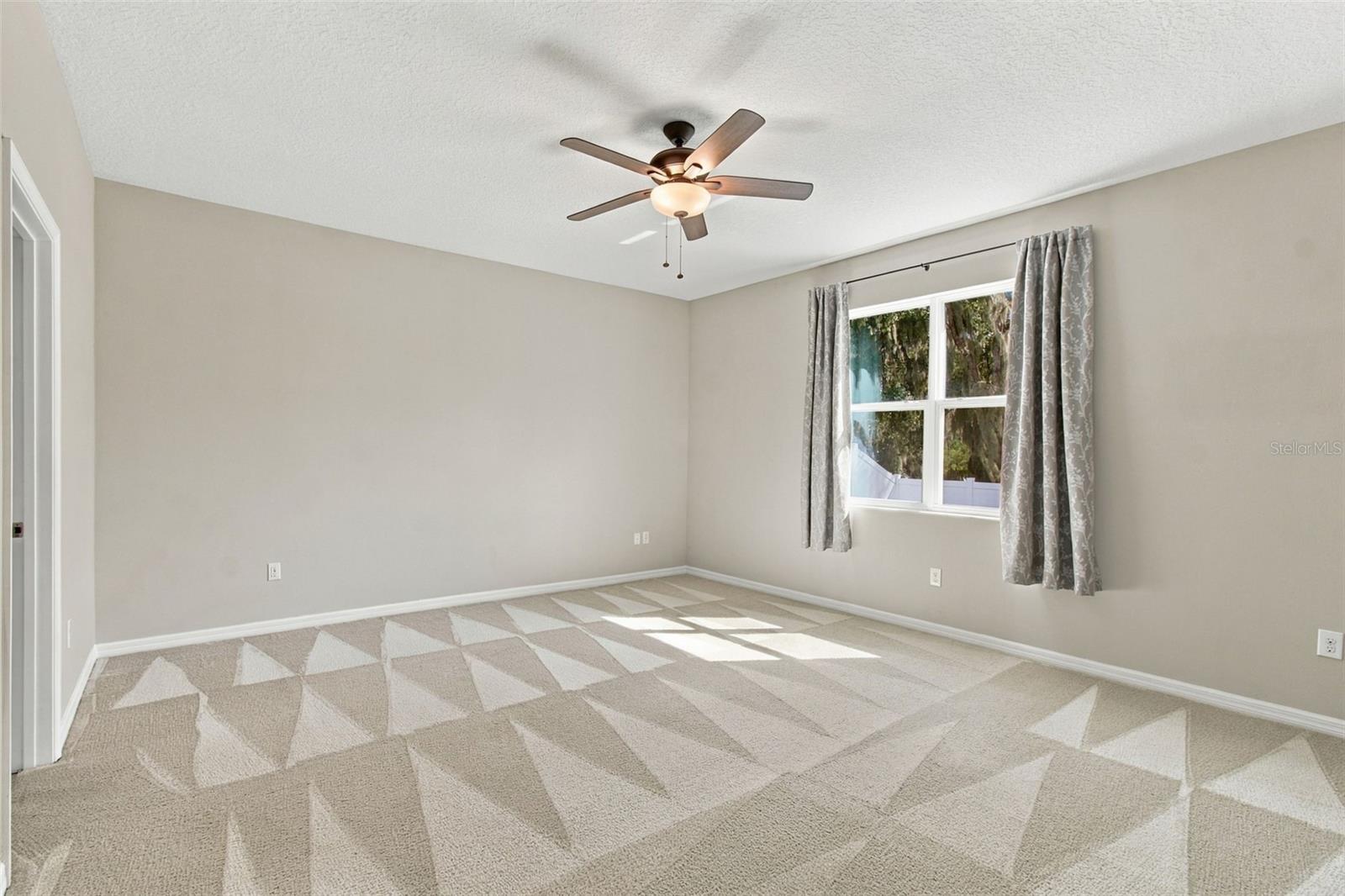 Primary Suite with ceiling fan and view of backyard oasis
