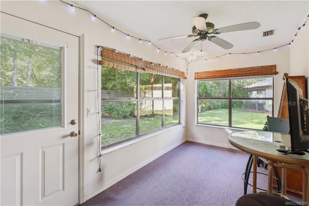 Enclosed rear porch with windows overlooking the backyard and sliding glass doors connecting to the interior.