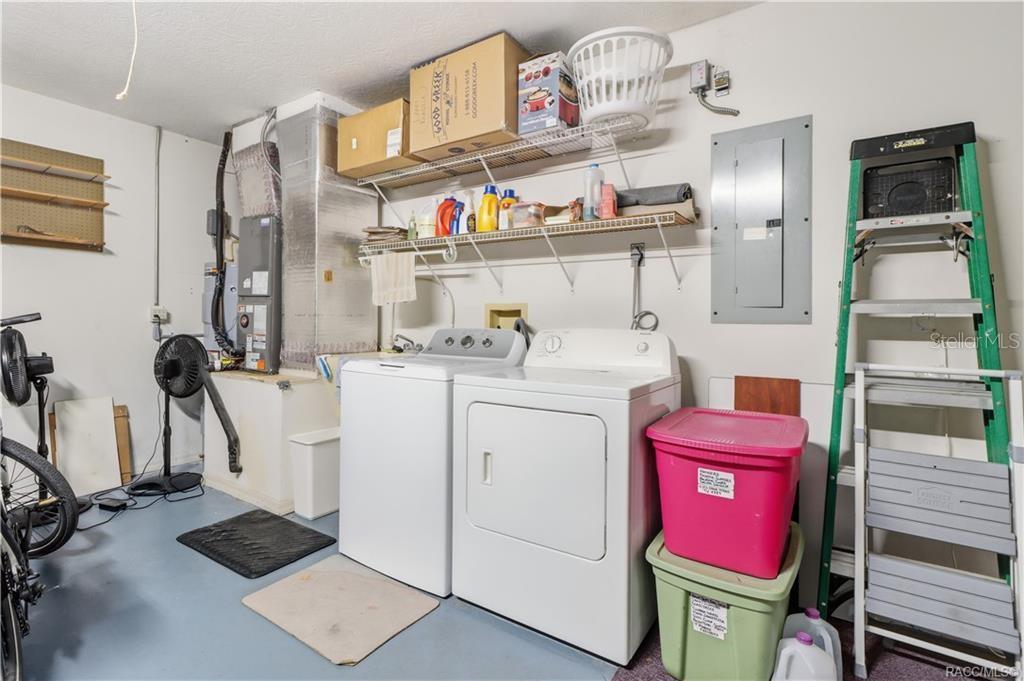 Garage laundry area with washer, dryer, overhead storage shelving, and additional storage space