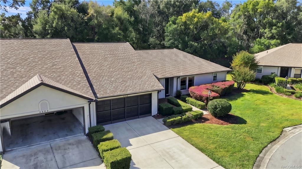 Aerial front view highlighting the home's attractive roofline, attached two-car garage, manicured landscaping, and cul-de-sac setting.