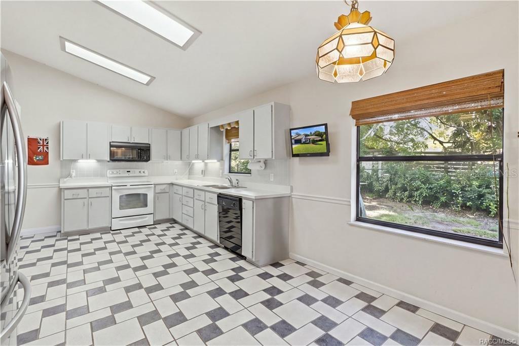 LET'S GET COOKING! Bright, spacious EAT-IN KITCHEN features WHITE CABINETRY, ample counter space, TILE FLOORING & a VAULTED CEILING!