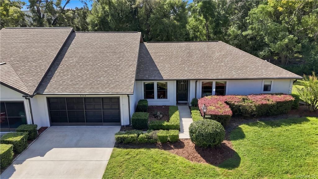 Front aerial view featuring the attached garage, welcoming entrance, neatly maintained landscaping, and attractive curb appeal.