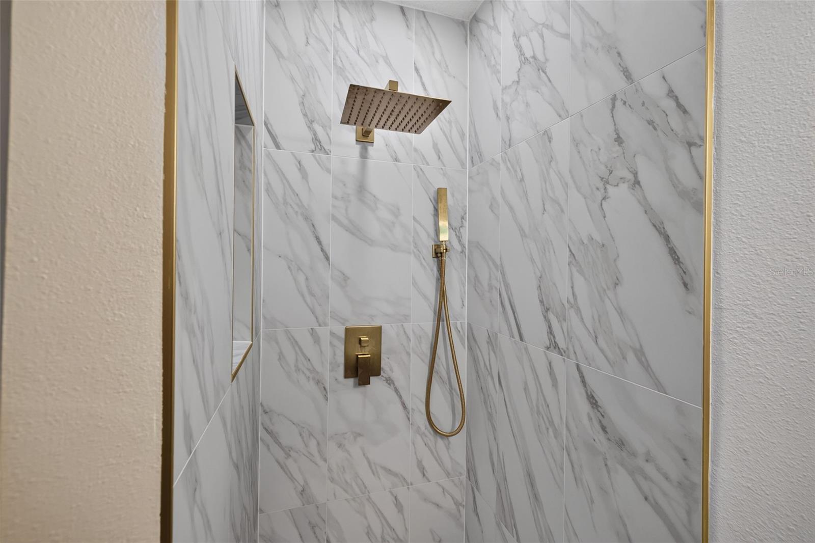 Step-in shower showcases beautiful new tile and stylish gold fixtures.