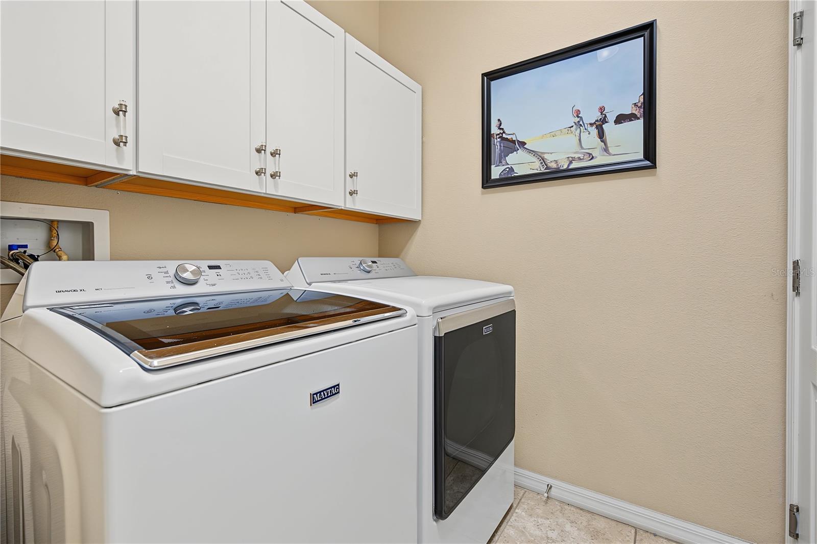 Interior laundry room with storage cabinets above