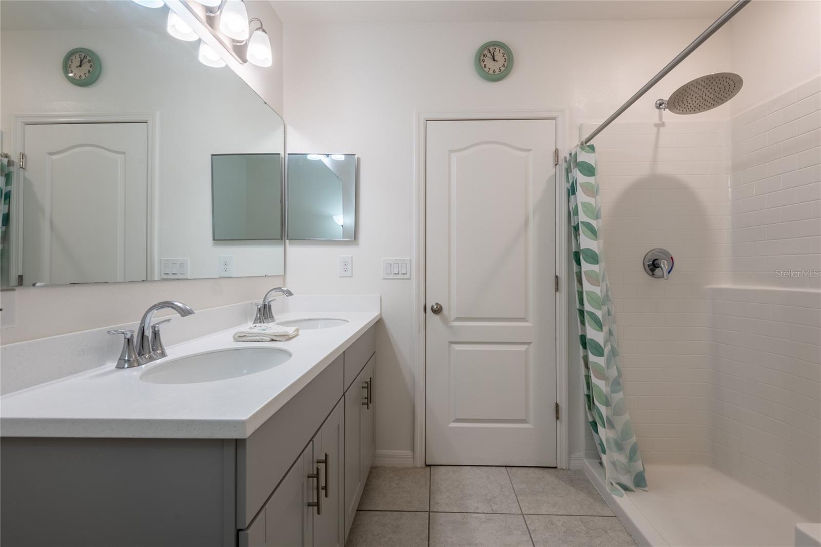 Primary bathroom with walk in shower and double sinks. Shaker cabinets and quartz counter tops.