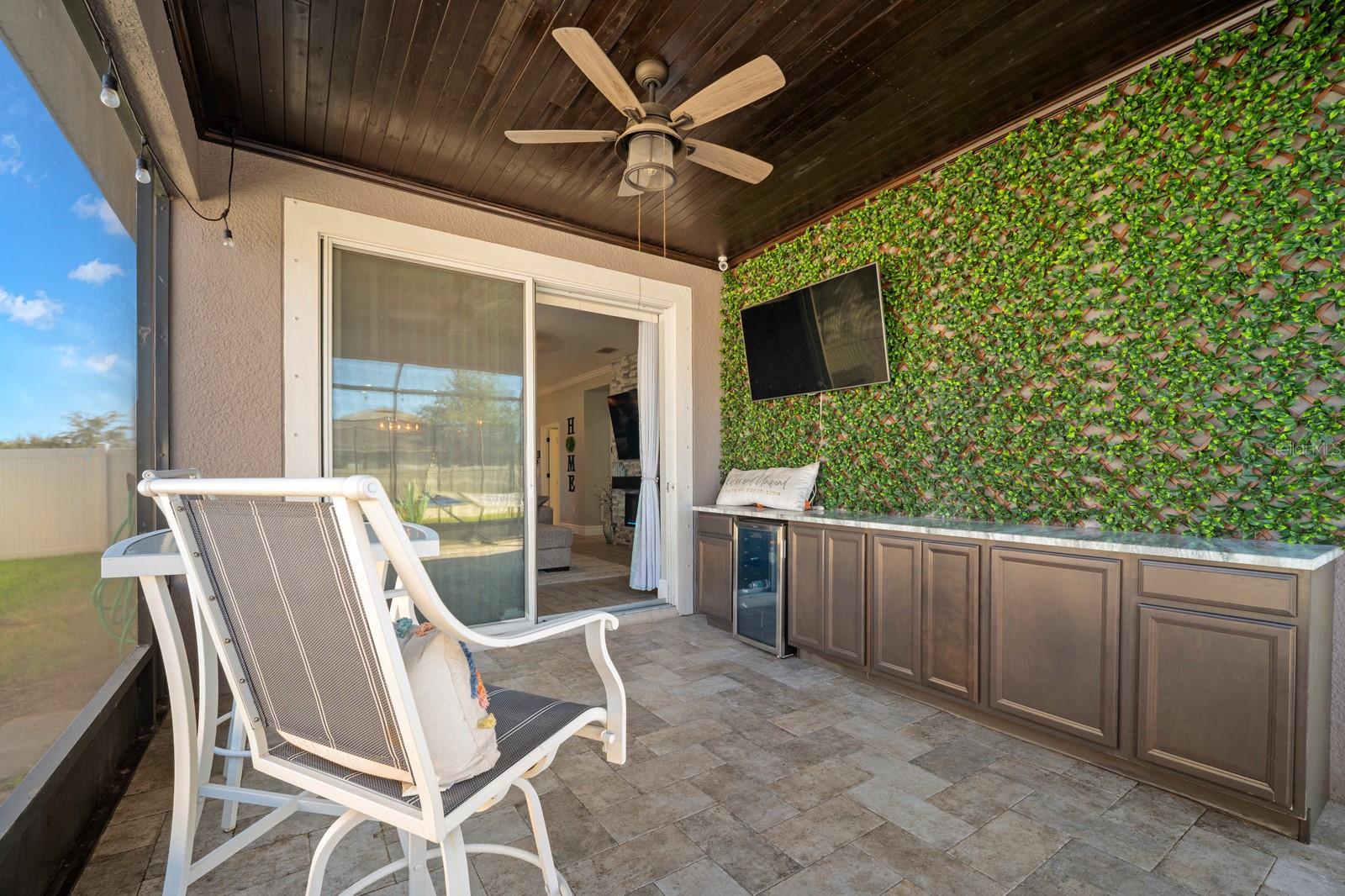 Covered lanai with outdoor kitchen, ceiling fan and mounted TV