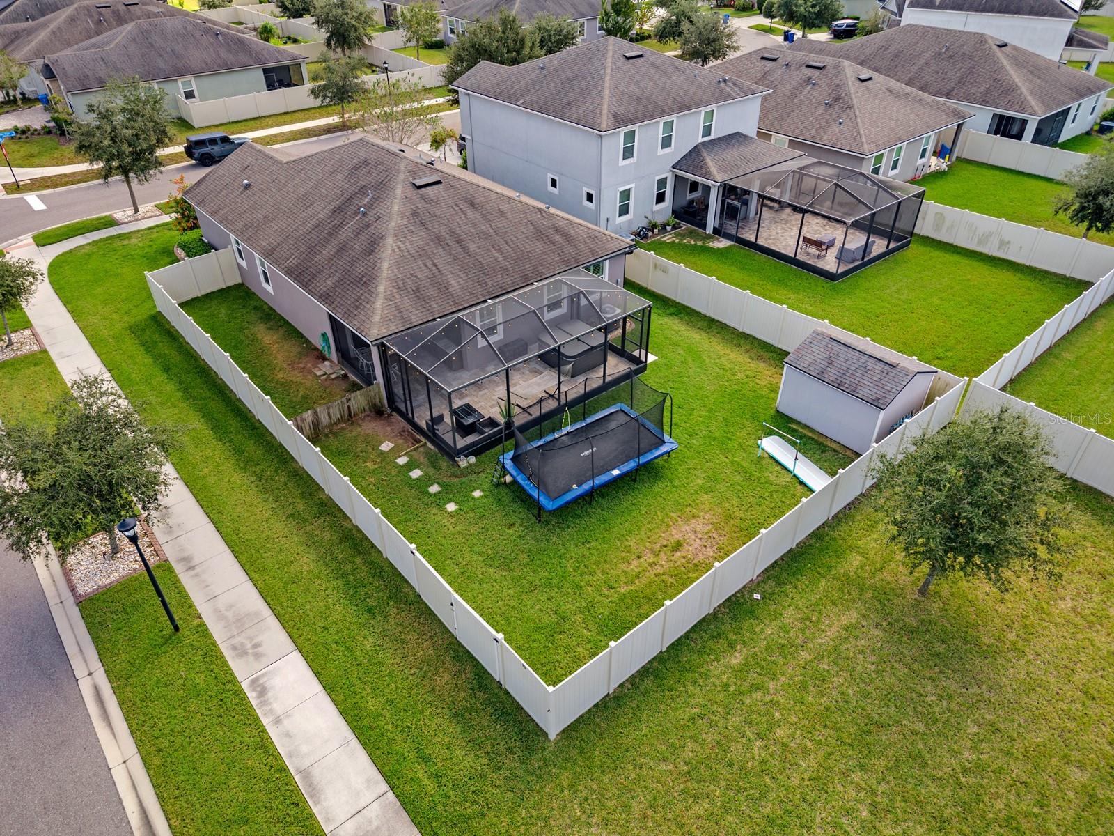 Aerial view of the fenced backyard, screened lanai and shed