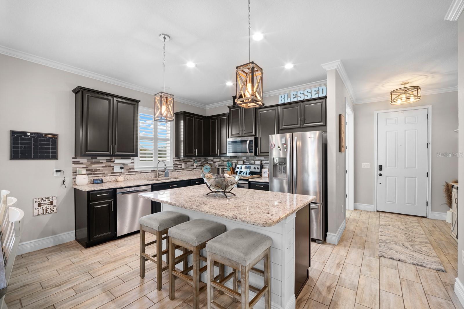 Kitchen with large granite island, breakfast bar seating and stainless appliances