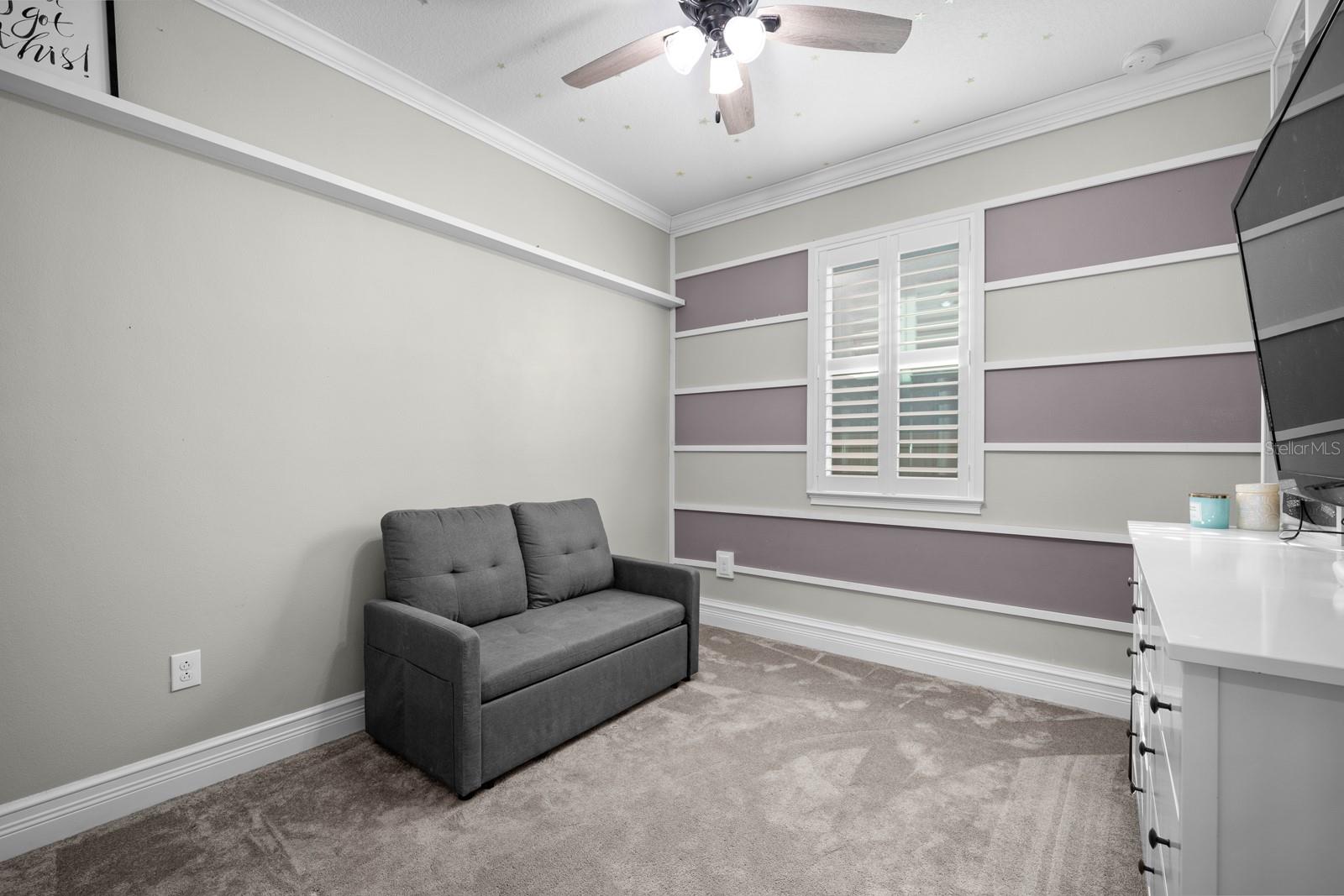 Bedroom with accent wall, ceiling fan and plantation shutters