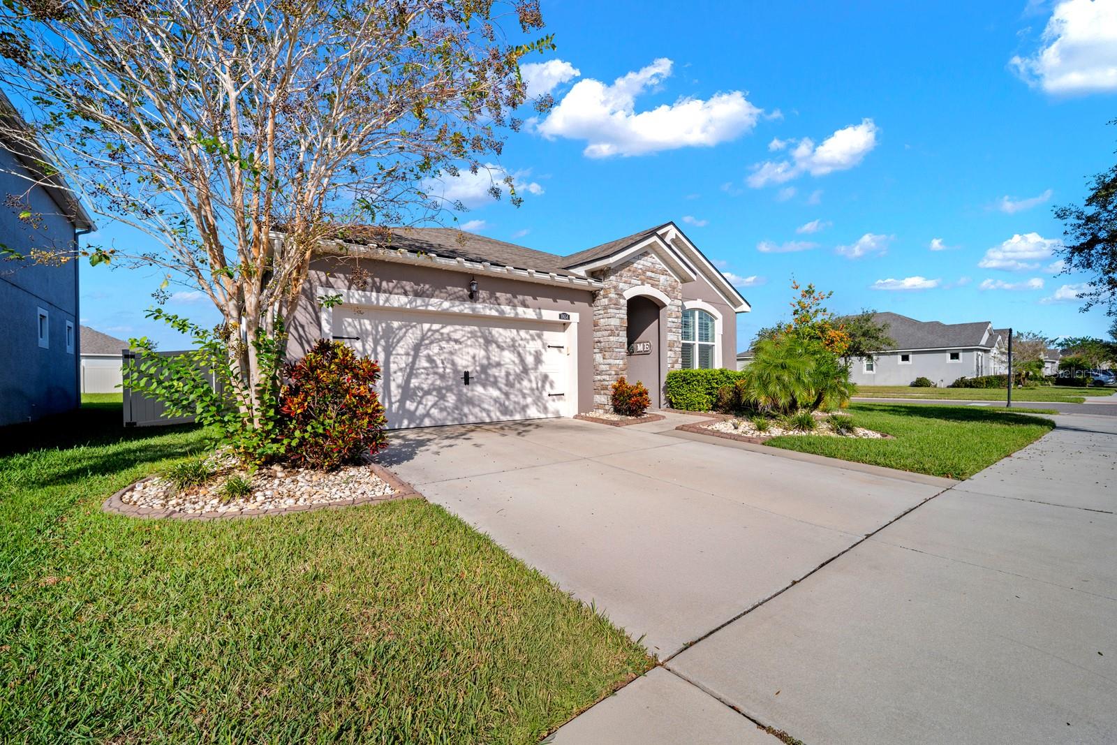 Street view of the home with wide driveway and established front yard