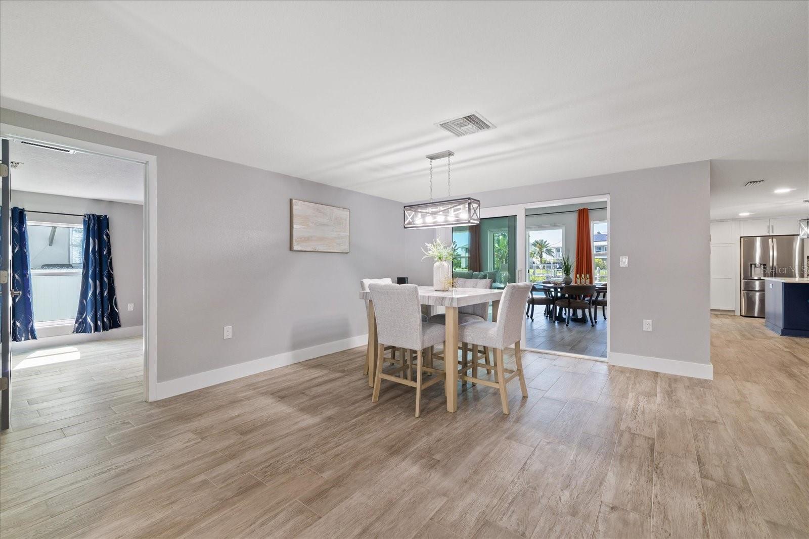 View from entry of primary bedroom entry and family room sliders past dining table