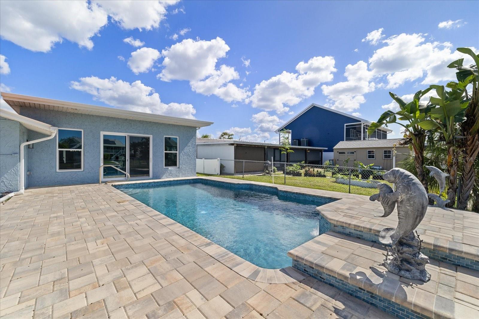 Pavered pool deck with dolphin accents and waterfall feature