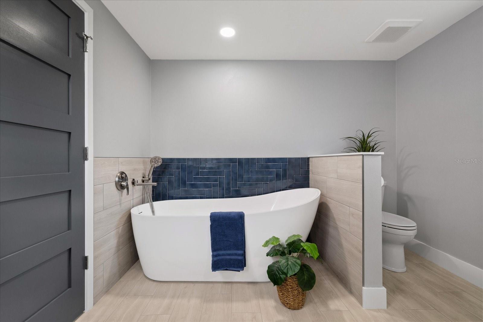 Luxury soaking tub in primary near walk-in closet